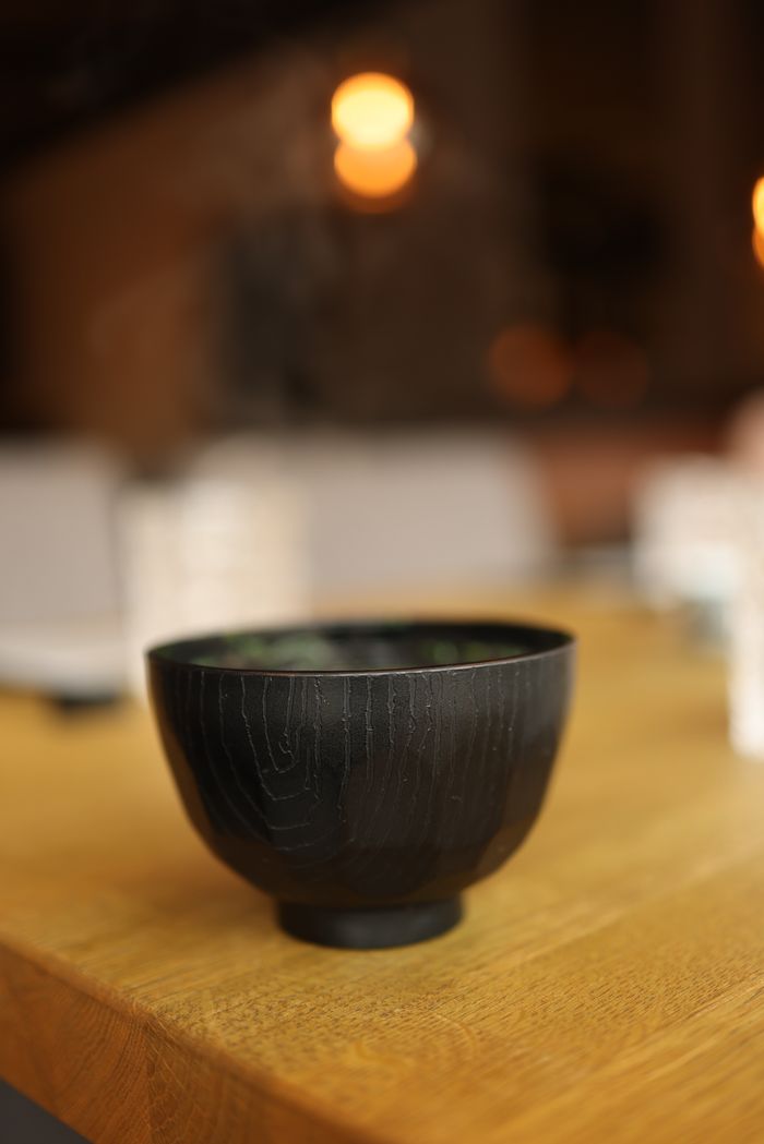Close-up of a wooden bowl on a table with blurred restaurant background.